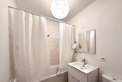 une salle de bain blanche avec un lavabo et une douche dans l'établissement Cozy studio à 4min du Metro avec parking privé, à Créteil