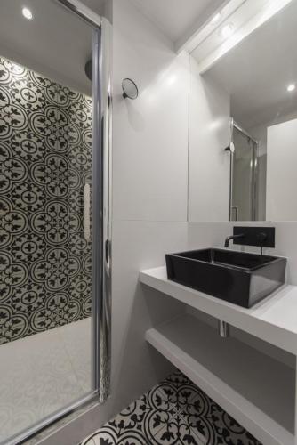 une salle de bain avec un lavabo noir et un miroir dans l'établissement Yacht, à Paris