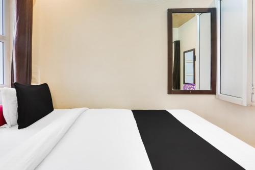 a bedroom with a white bed and a mirror at Super Hotel O Jamrani Formerly White House in Haldwāni