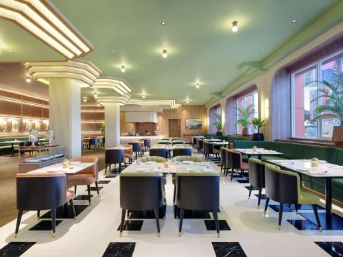 a dining room with tables and chairs and windows at Mercure Garut City Center in Garut