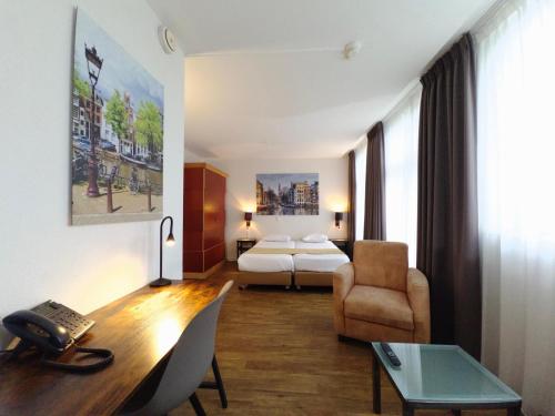 een hotelkamer met een bed en een bureau bij Hotel Residence Le Coin in Amsterdam