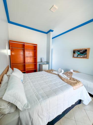a bedroom with a large white bed with a blue stripe at Hotel Paraiso Maragogi LTDA in Maragogi