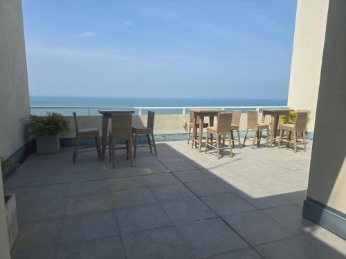a patio with tables and chairs on the beach at Luxury Beachfront Apartment in Bopitiya
