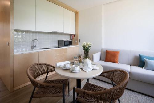 a kitchen and a living room with a table and chairs at Lusitano Garden Villas in Ponta Delgada