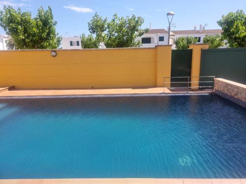 a swimming pool in front of a yellow fence at Villa Tonia in Cala en Blanes