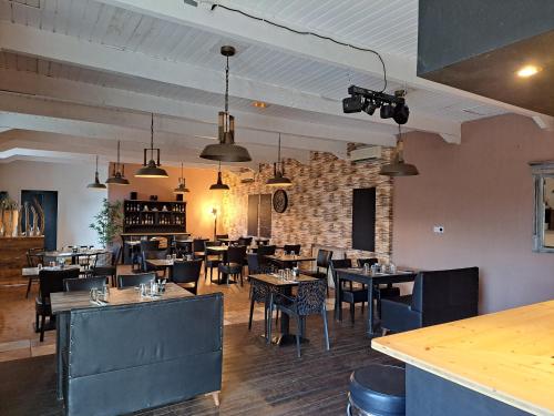 un restaurant avec des tables et des chaises et un mur de briques dans l'établissement Logis Hotel Restaurant Les Platanes, à Aramon
