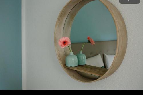 a mirror with vases and flowers on a wall at Strandhaus am Wörthersee in Velden am Wörthersee