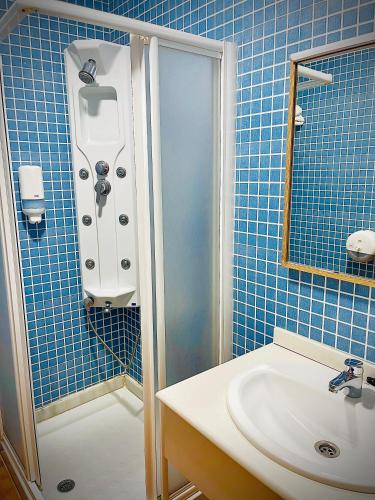 a blue tiled bathroom with a shower and a sink at Hostal Restaurante Bustos in Villarrubio