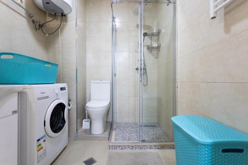 a bathroom with a shower and a washing machine at Cozy place New Boulevard in Batumi