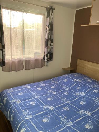 une chambre avec un lit bleu avec une fenêtre dans l'établissement Camping domaine de Litteau en Normandie, à Litteau