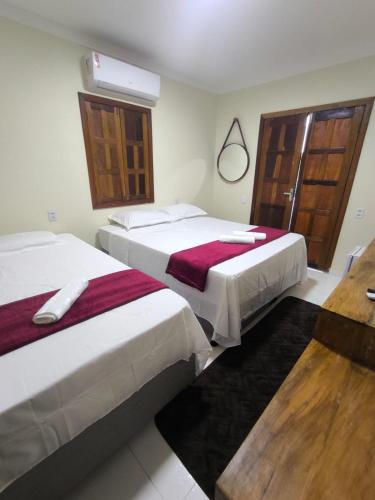 Una habitación de hotel con dos camas y una ventana. en Vila Bahia suítes, en Caraíva