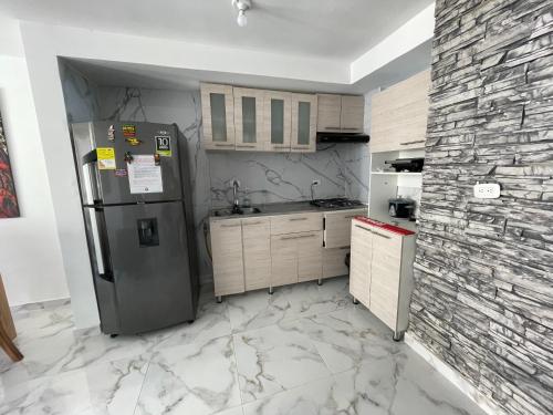 a kitchen with a refrigerator and a stone wall at Fontana campestre in Ibagué