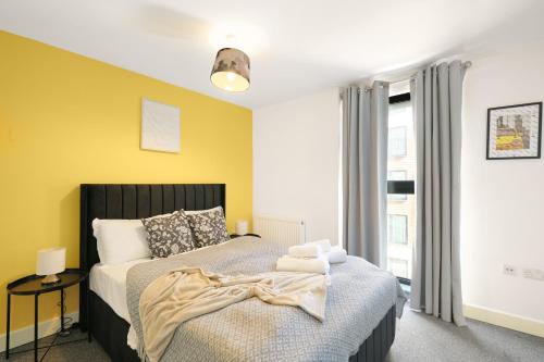 a bedroom with a bed and a yellow wall at Affordable 1 & 2 Bed Apartments in Slough, Great Heathrow Location in Colnbrook