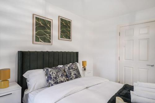 a bedroom with a bed with a green headboard at Affordable 1 & 2 Bed Apartments in Slough, Great Heathrow Location in Colnbrook