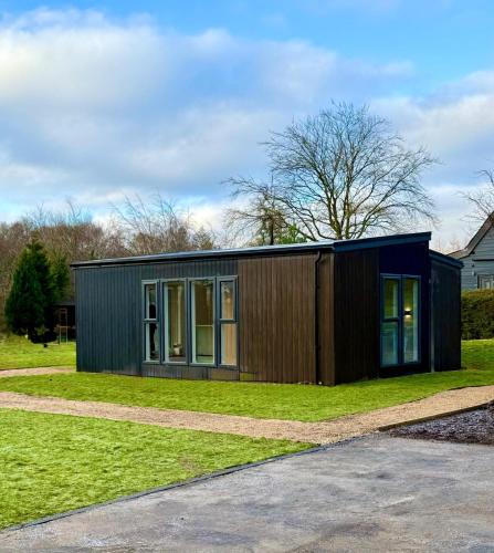 a small black house on a grass field at Loch Lomond Waterfront Luxury Lodges in Balmaha