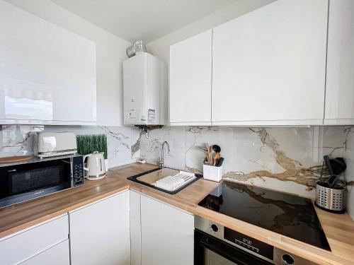 une cuisine avec des armoires blanches et un comptoir dans l'établissement Juan les pins Studio détente Vacances & Mer, à Juan-les-Pins