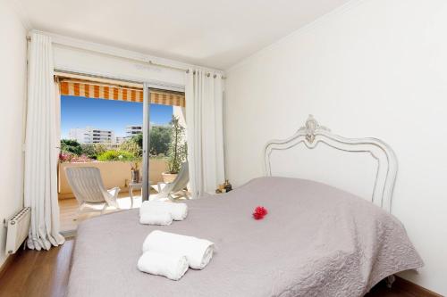 une chambre blanche avec un grand lit avec deux serviettes dans l'établissement Echappée paisible à Antibes, à Antibes