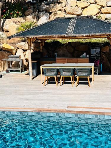 - une table de pique-nique et des chaises à côté de la piscine dans l'établissement Villa Cala d Oro Vue mer Piscine et Crique privée, à Sari-Solenzara