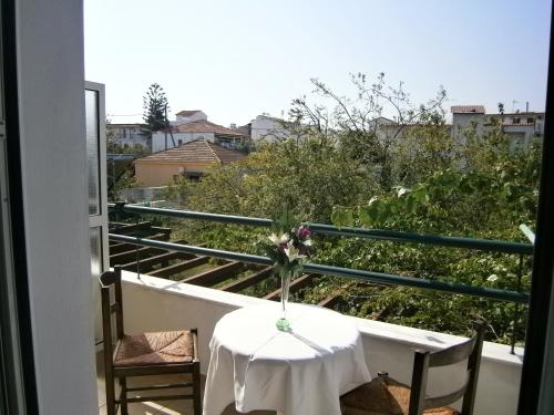 a table with a vase of flowers on a balcony at Pansion Chrisa in Skiathos Town