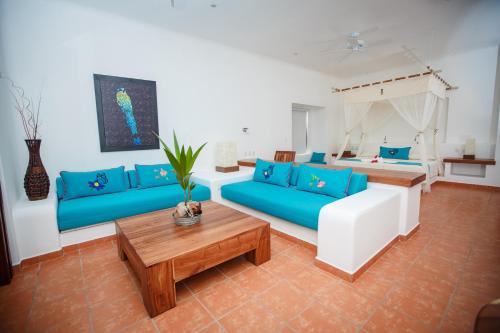 a living room with blue couches and a bed at Hotel Rancho Encantado in Bacalar