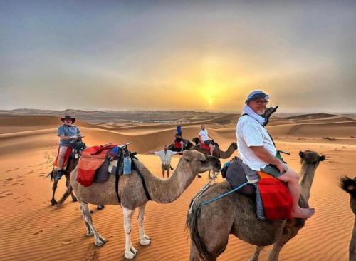 a group of people riding on camels in the desert at Fantastic Luxury Camp in Merzouga