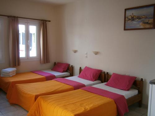 a room with three beds with orange and pink sheets at Pansion Chrisa in Skiathos Town