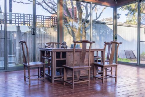 a wooden table with three chairs around it at Puddings Tranquil Sunroom Retreat in Glen Waverley in Glen Waverley
