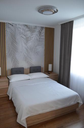 a bedroom with a white bed with a wall mural at ApartHotel 3 in Negreşti-Oaş