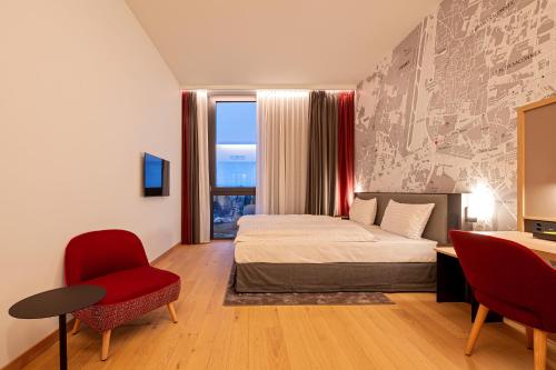 a bedroom with a bed and a desk and a window at IntercityHotel Geneva in Geneva