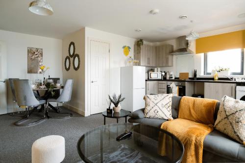 a living room with a couch and a table and a kitchen at Affordable 1 & 2 Bed Apartments in Slough, Great Heathrow Location in Colnbrook