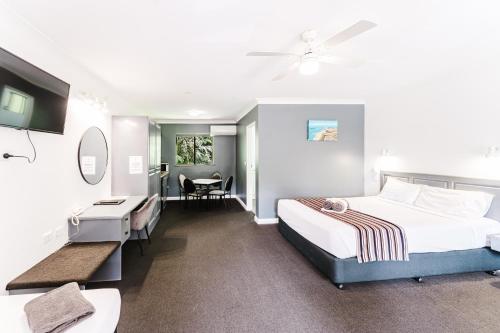 a hotel room with two beds and a desk at Country 2 Coast Motor Inn Coffs Harbour in Coffs Harbour