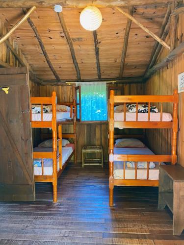 a room with three bunk beds in a cabin at Haleakala Hostel & Pousada in Praia do Rosa