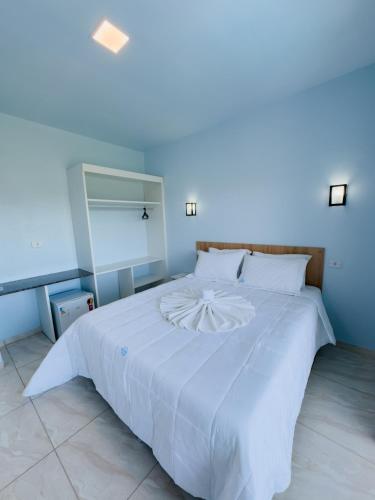 a white bed in a room with a blue wall at Hotel Paraiso Maragogi LTDA in Maragogi