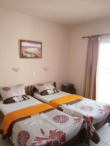 two beds in a room with a window at Pansion Chrisa in Skiathos Town