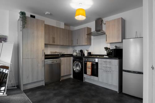 a kitchen with wooden cabinets and a washer and dryer at Affordable 1 & 2 Bed Apartments in Slough, Great Heathrow Location in Colnbrook