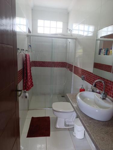 a white bathroom with a toilet and a sink at Quarto Privativo Santa Rita do Sapucaí in Santa Rita do Sapucaí