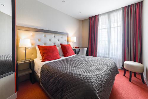 a hotel room with a bed with red pillows at Eiffel Kennedy in Paris