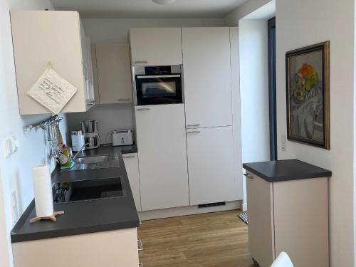 a kitchen with white cabinets and a white refrigerator at Tor zum Meer in Helgoland