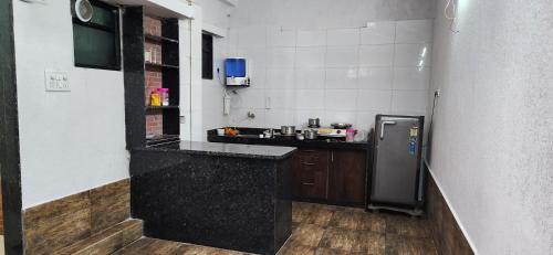 a kitchen with a black counter and a refrigerator at Gotawala Villa 11 in Daman