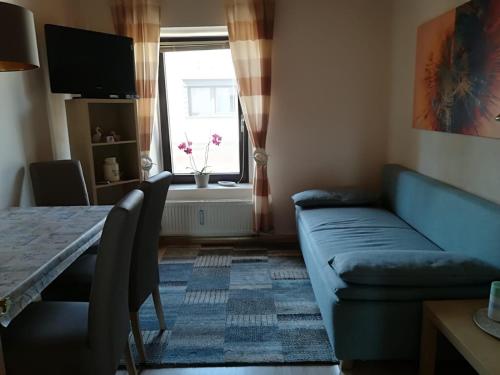 a living room with a blue couch and a window at Ferienwohnungen Thul in Schweich