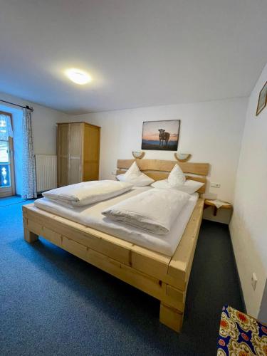 a bedroom with a wooden bed with white sheets at Bergbauernhof Klauslehen in Ramsau