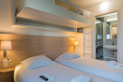 a hotel room with two beds and a mirror at TERNELIA Le Vent Du Large in Saint-Gilles-Croix-de-Vie
