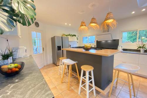 une cuisine avec un îlot avec des tabourets et un comptoir dans l'établissement Superb contemporary villa with pool and garden, à Roquefort-les-Pins
