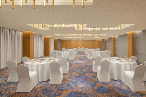 a banquet hall with white tables and white chairs at Courtyard by Marriott Goa Colva in Colva