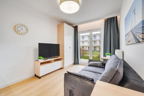 a living room with a couch and a tv at ReVital Mechelinki by Homeprime Parking Free in Mechelinki