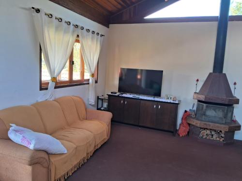 a living room with a couch and a flat screen tv at Cantinho da Serra in Santo Antônio do Pinhal