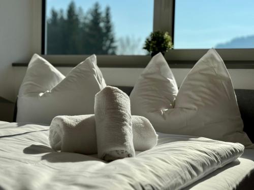 a white bed with white pillows and a stuffed animal on it at TALBLICK - Apartment mit Panorama in Treffen