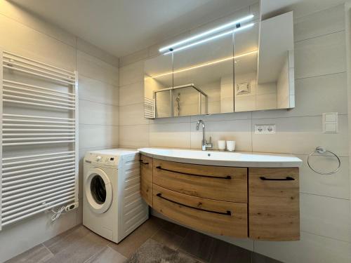 a bathroom with a sink and a washing machine at TALBLICK - Apartment mit Panorama in Treffen