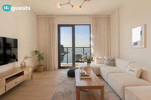 a living room with a white couch and a large window at HiGuest - Elegant 1BR Oasis in La Mer in Dubai