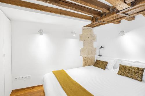 - une chambre blanche avec un lit dans un dortoir doté de plafonds en bois dans l'établissement Petit Chalet, à Paris